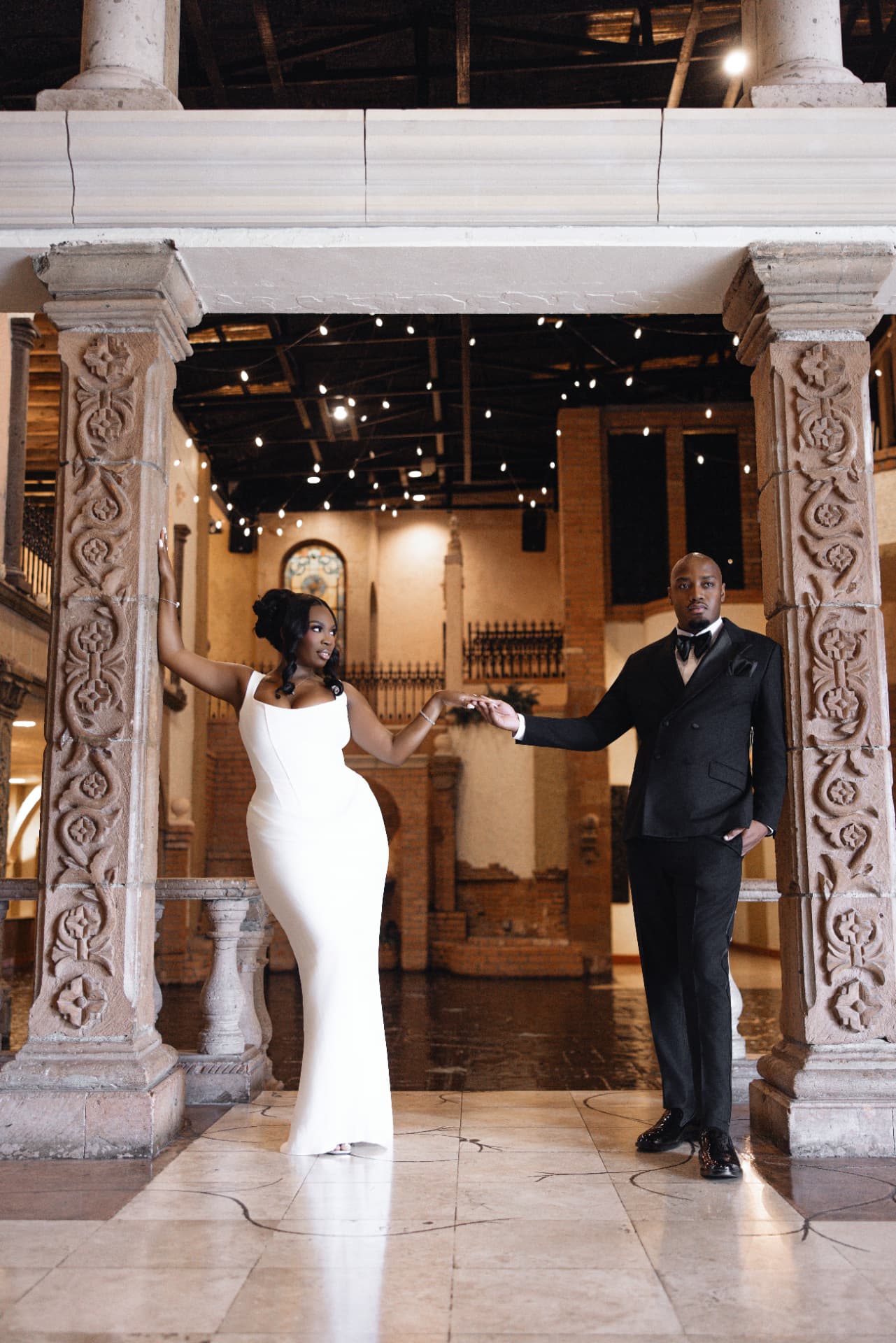 Bride and groom holding hands beneath carved stone columns
