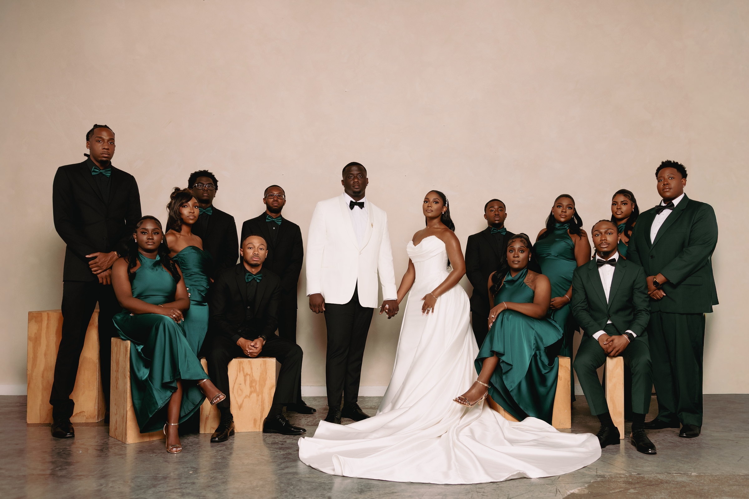 Bride and groom with their wedding party in emerald green and black formalwear