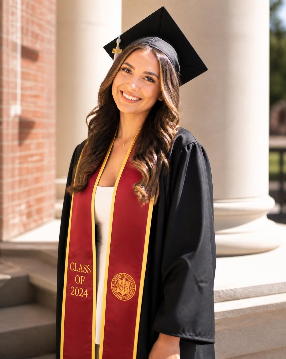 Graduate in cap, gown and stole smiling in front of campus columns